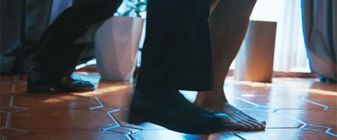 Bare feet on a wooden floor with glowing tile outlines and backlighting in the background.