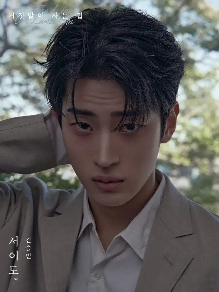 Close-up portrait of a young man in a beige suit, with his hand behind his head, gazing at the camera against a blurred outdoor background; Korean text overlays.