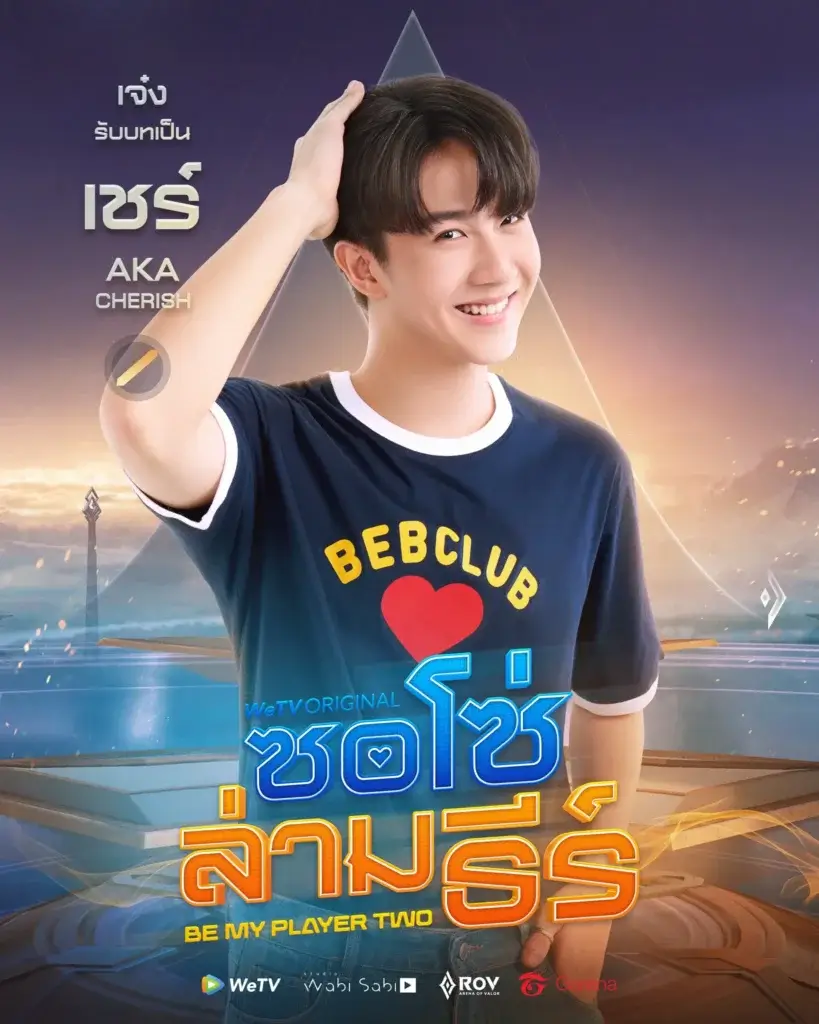 Smiling young man in a navy T-shirt posing in front of a colorful promotional poster for a Thai show, with logos at the bottom.