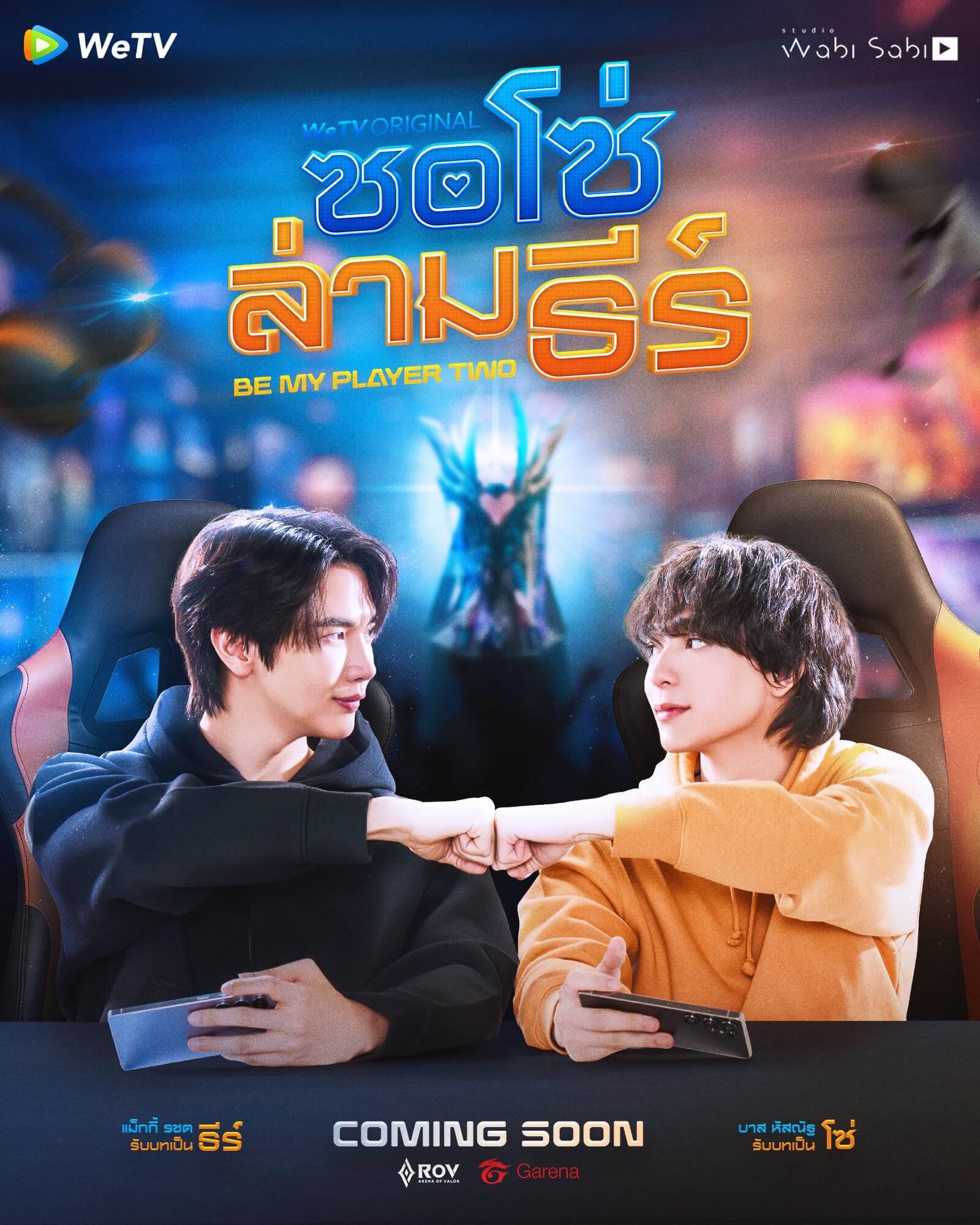 Two young men in racing chairs fist-bump while holding game controllers on a colorful poster that reads 'COMING SOON' at the bottom, with logos.