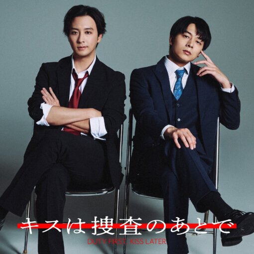 Two men in suits sit on chairs against a gray backdrop, legs crossed, posing confidently; poster text at bottom reads 'Duty First, Kiss Later' (in red).