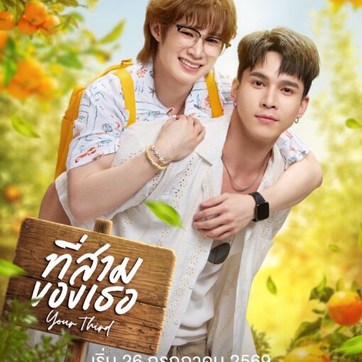 Two young men outdoors, one giving the other a piggyback, smiling, holding a wooden sign with Thai script amid bright orange trees and greenery.
